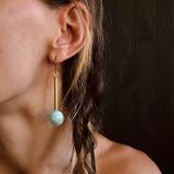 Model wearing CIVAL Colelctive's "Marit" drop earrings with brass bar and light green seraphinite round.