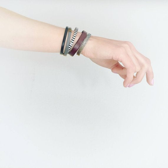 Model's arm layered with 5 different leather & fabric bracelets designed and made by Cival Collective.