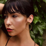 Model wearing CIVAL Collective's "Rilo" textured brass circle earrings.