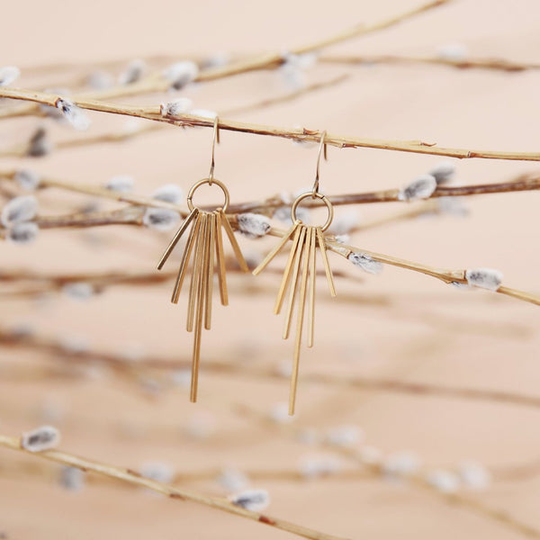 Close up of "Yuki" brass fringe earrings that have 7 brass tabs on a ring creating a starburst effect.